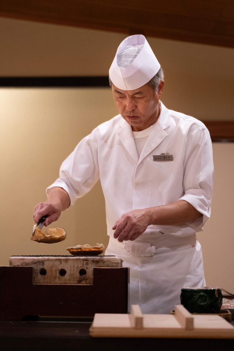 焼き場で調理する料理人の写真